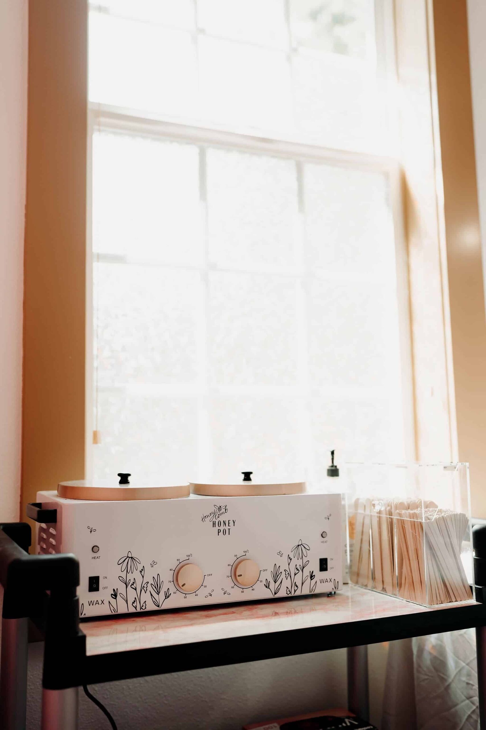 Wax warmer with floral design, wooden sticks, and natural window light.